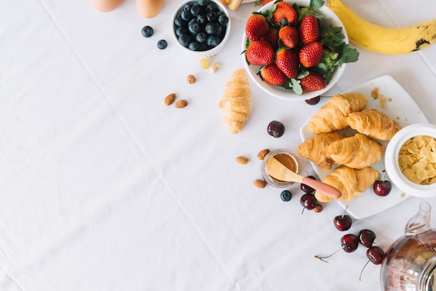 An overhead view of fresh fruits and croissant on dinning table