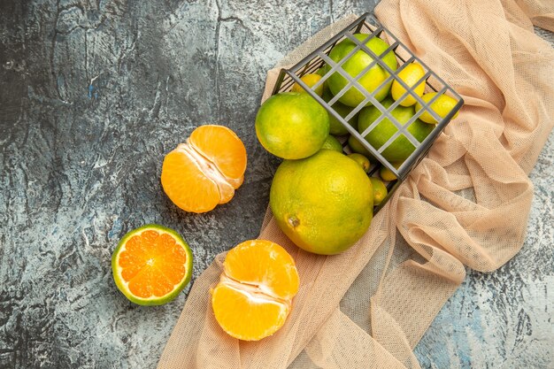 Vista dall'alto di limoni freschi in un cesto nero caduto su un asciugamano su un tavolo grigio fotografia stock