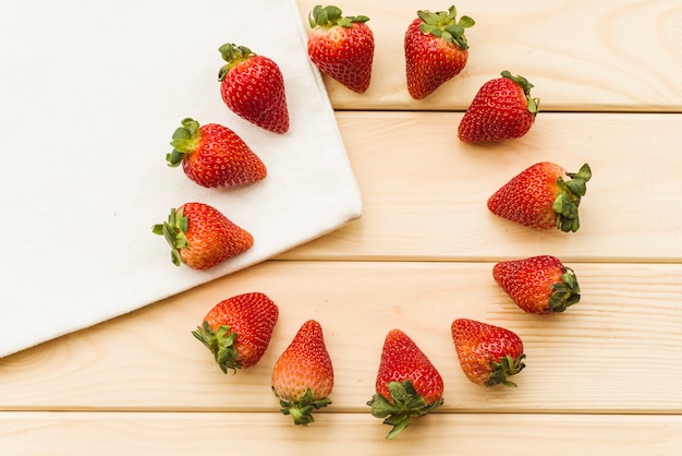 Overhead view of fresh strawberries forming circles on wooden background