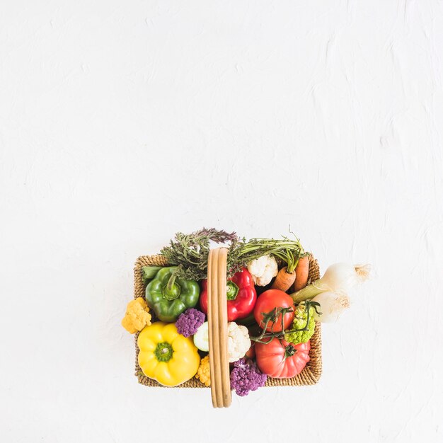 テクスチャ付きの背景上のバスケットの新鮮な野菜のオーバーヘッドビュー