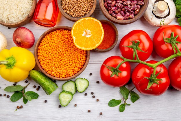 Overhead view of fresh vegetables corn kernels bundle of greens mushroom on white background