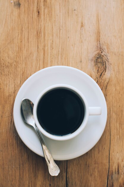 An overhead view of a freshly brewed black coffee cup on wooden textured background