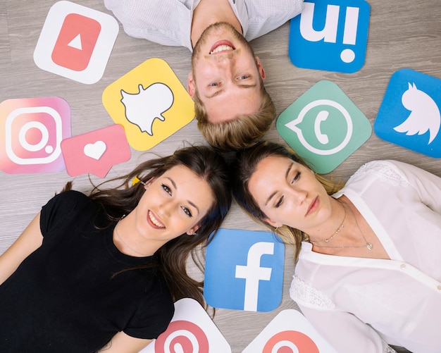 Free photo overhead view of friends lying on backdrop with social media icons