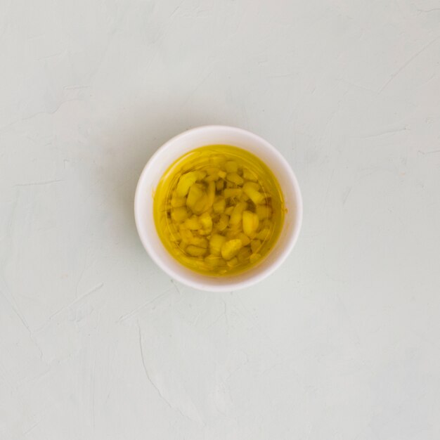 Вид сверху чеснока настоянного оливкового масла в миске на белом фоне текстурированных