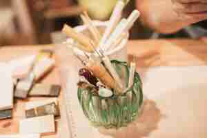 Free photo an overhead view of glass holder with different type of hand tools on wooden desk