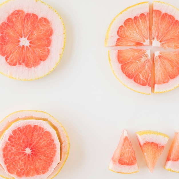 An overhead view of grapefruit cut in different shape and slice over the white backdrop