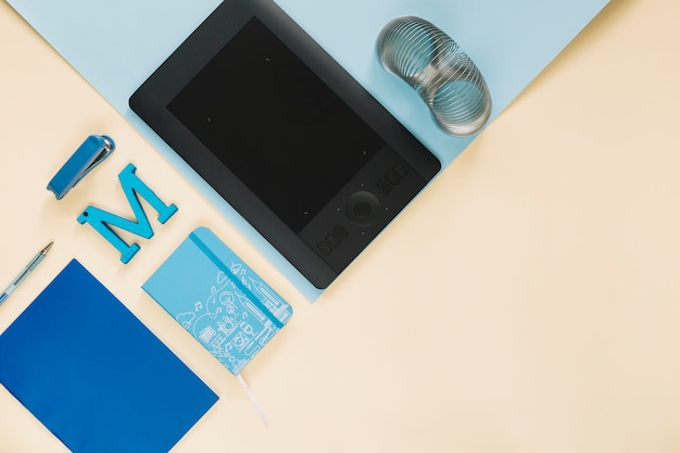 Overhead view of graphic digital tablet and stationeries on paper backdrop