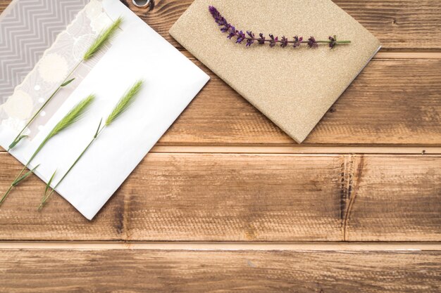 Overhead view of green ears of wheat on greeting card and lavender twig on wooden table