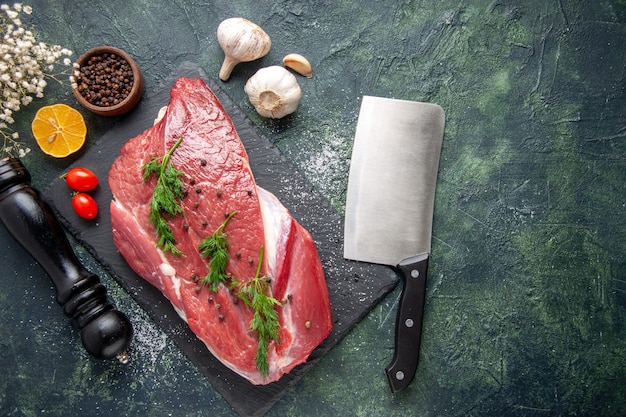 まな板の新鮮な赤い生肉と緑の黒のミックスカラーの背景にペッパーレモンブラックハンマーの花の緑の俯瞰図