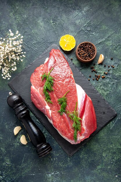 Overhead view of green on fresh red raw meat on cutting board and pepper lemon black hammer flower on green black mix color background