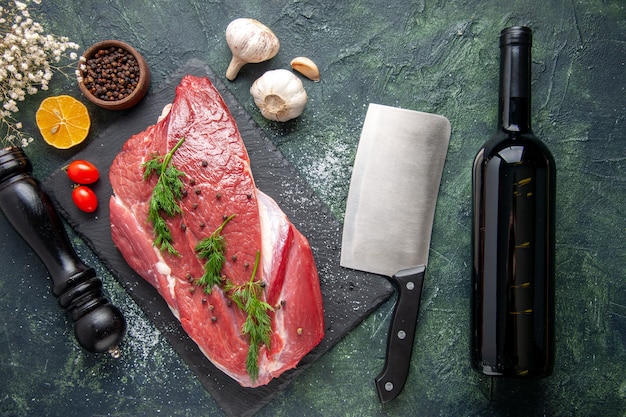 Overhead view of green on fresh red raw meat on cutting board and pepper lemon black hammer flower wine bottle on green black mix color background