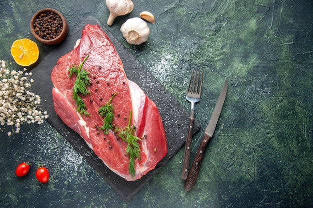 Overhead view of green on fresh red raw meat on cutting board and pepper lemon flower on green black mix color background