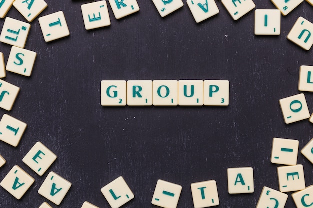 Overhead view of group text on scrabble letters over black backdrop