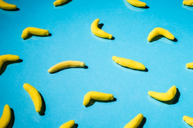 Free photo overhead view of gummy banana candies on blue backdrop