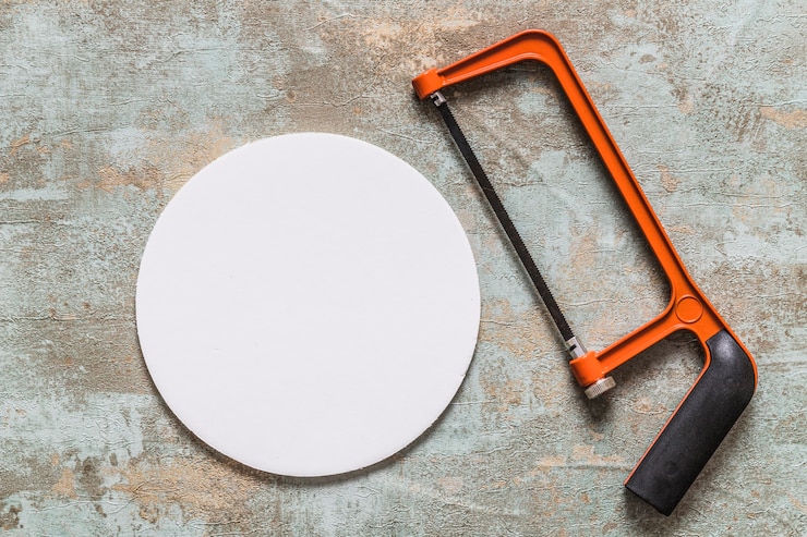 Free Photo overhead view of hacksaw and white circular frame