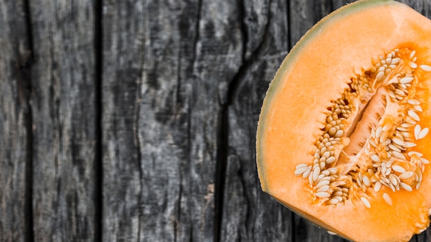 Free photo an overhead view of halved musk melon on an old wooden backdrop