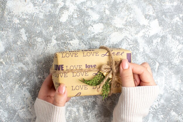 Overhead view of hand holding packed gift for Christmas on ice surface