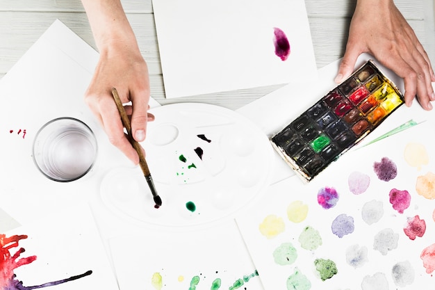 Overhead view of hand mixing watercolor for painting