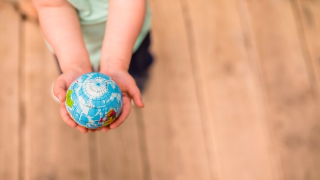 An overhead view of hands holding globe ball against hardwood floor