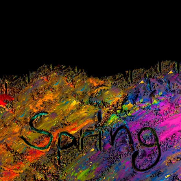 Overhead view of handwritten spring text on colorful holi powder