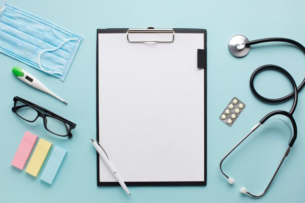 Overhead view healthcare accessories near clipboard with plank paper and spectacles on background