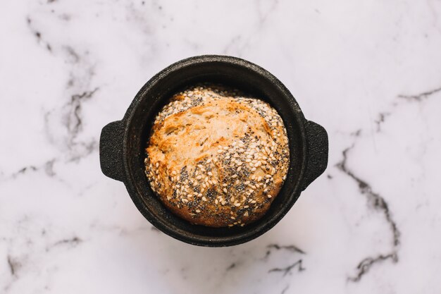 An overhead view of healthy bread with seeds in the container on marble top