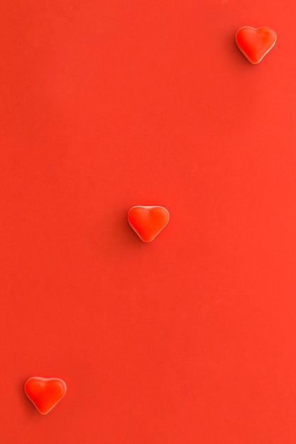 Overhead view of heart shape candies on red surface