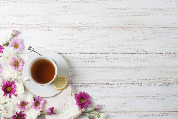 Вид сверху чашку травяного чая с цветами на окрашенный деревянный текстурированный фон