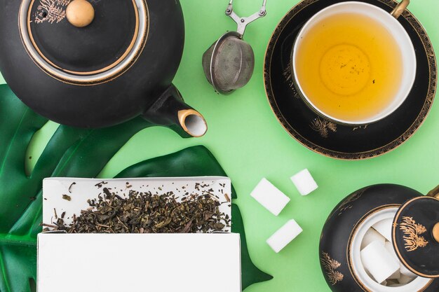Overhead view of herbal tea set on green background