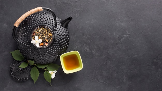 Overhead view of herbal tea with fresh white jasmine flower on black background