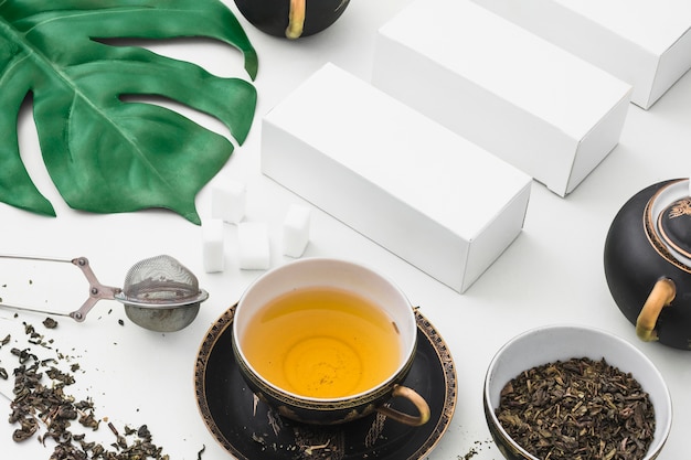 Overhead view of herbal tea with sugar cubes and white boxes on backdrop