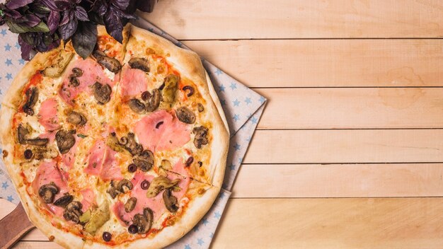 An overhead view of homemade pizza on wooden plank backdrop