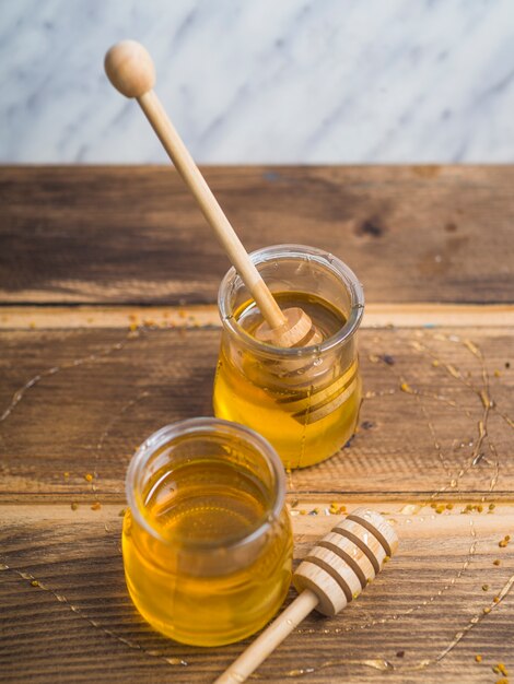 An overhead view of honey dipper with honey pot on wooden table