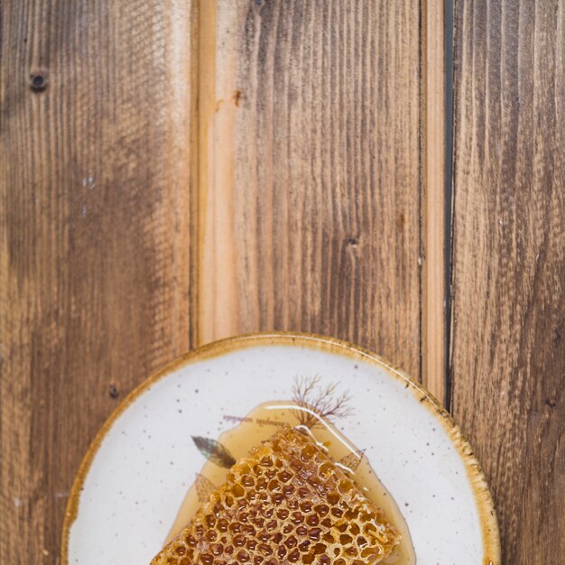 An overhead view of honeycomb on plate over wooden backdrop