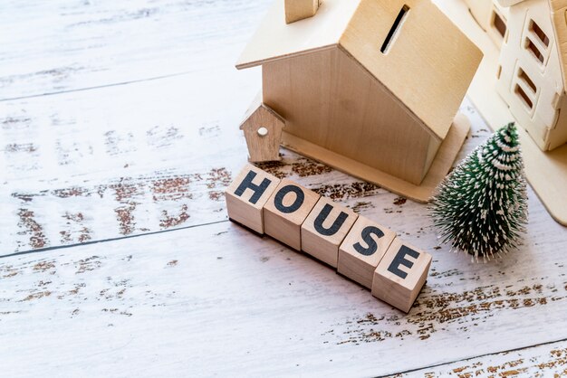 An overhead view of house model with house wooden blocks and christmas tree on white textured surface