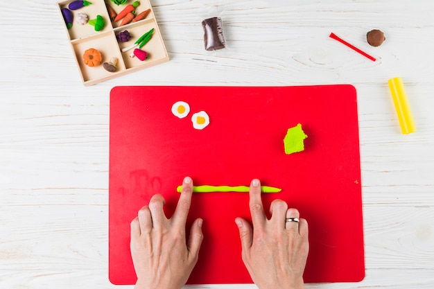 Overhead view of human hand making fruits and vegetable shape from clay