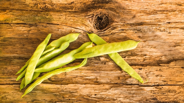 An overhead view of hyacinth bean on wooden textured backdrop