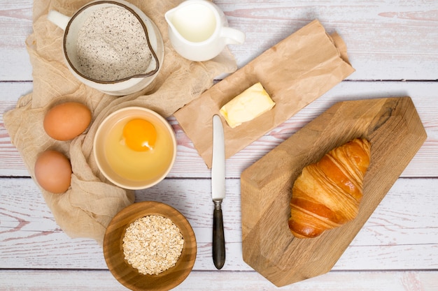 An overhead view of ingredients for making fresh baked croissant on wooden plank