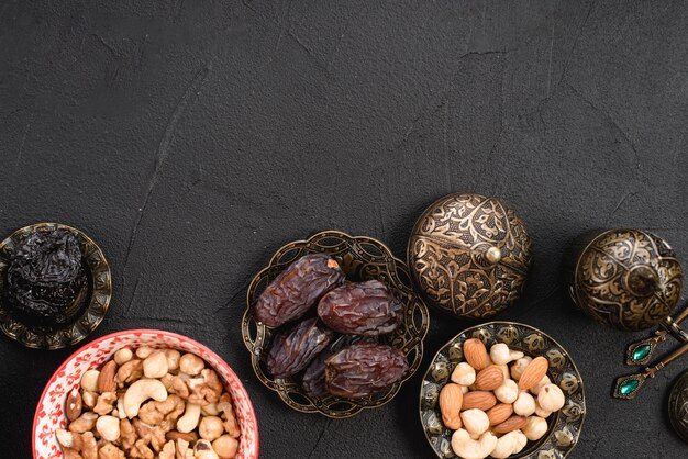 An overhead view of juicy delicious dates and nuts in metallic bowl on concrete background