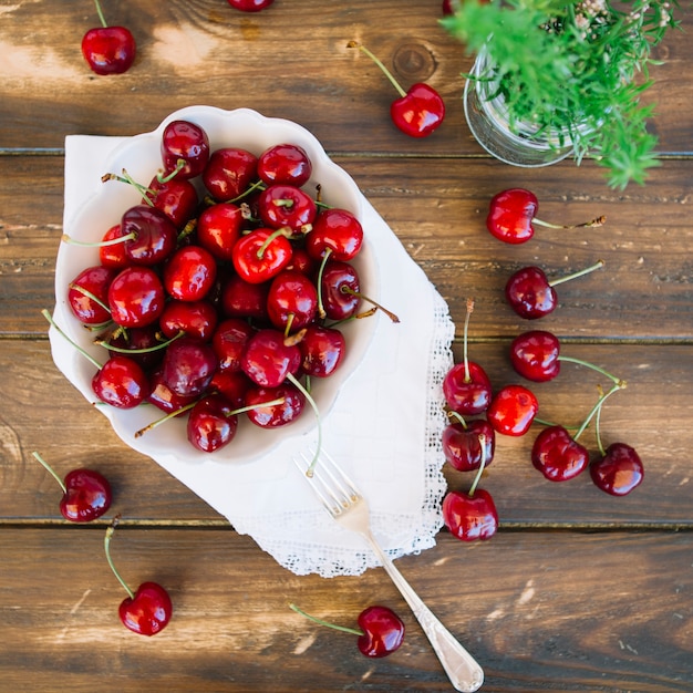 Free photo overhead view of juicy red cherries in bowl on wooden background