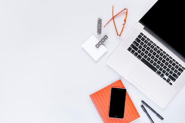 Overhead view of laptop and office stationery on white background