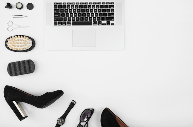 An overhead view of laptop with female accessories against white background