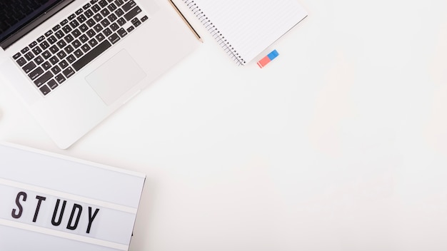 Overhead view of laptop with stationeries and study text on white background