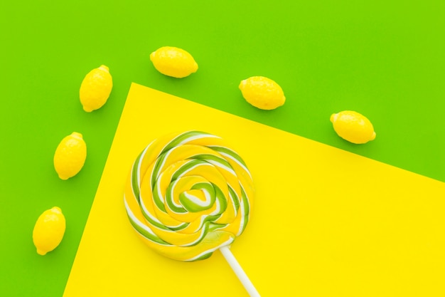 Overhead view of lemon candies and lollipop on dual yellow and green background