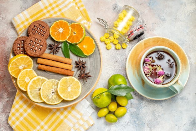 Overhead view of lemon slices cinnamon lime on a wooden cutting board and biscuits on white table