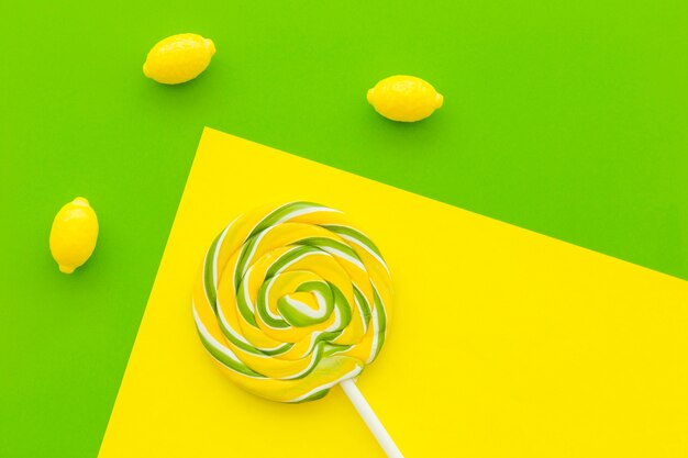 Overhead view of lollipop and lemon candies on multi colored background