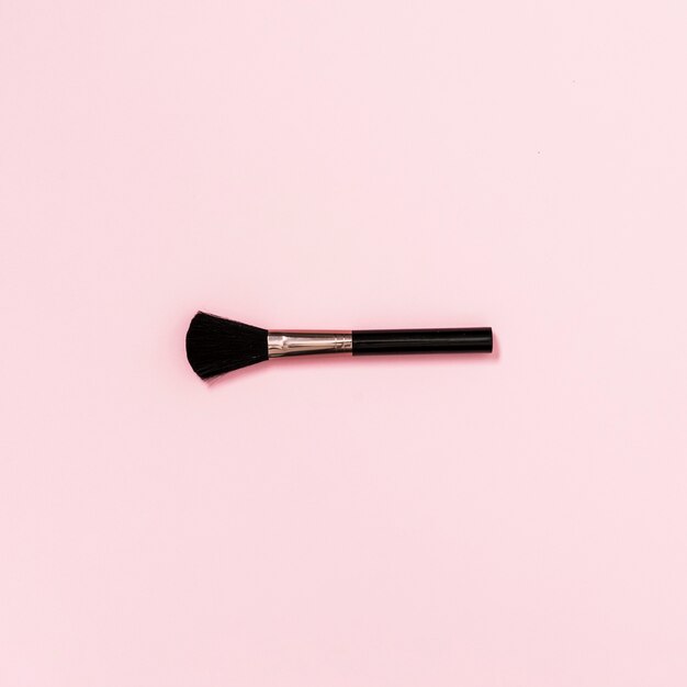 An overhead view of makeup brush against pink background