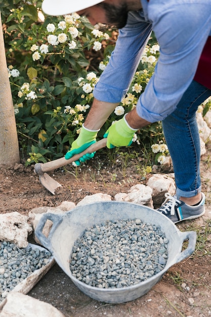 An overhead view of a male gardener digging the soil with hoe