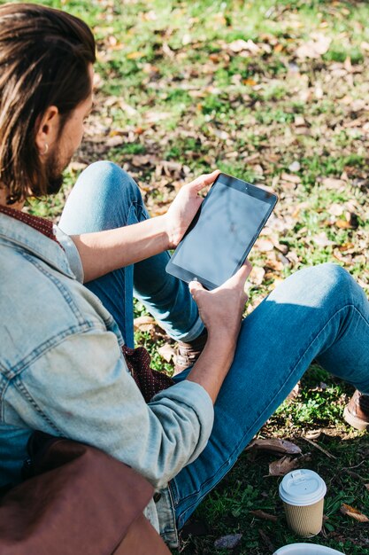 An overhead view of man sitting in the park using mobile phone