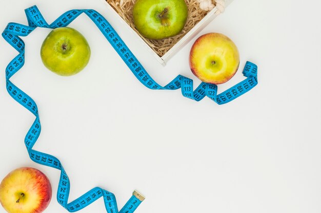 An overhead view of measuring tape with red and green apples isolated on white background